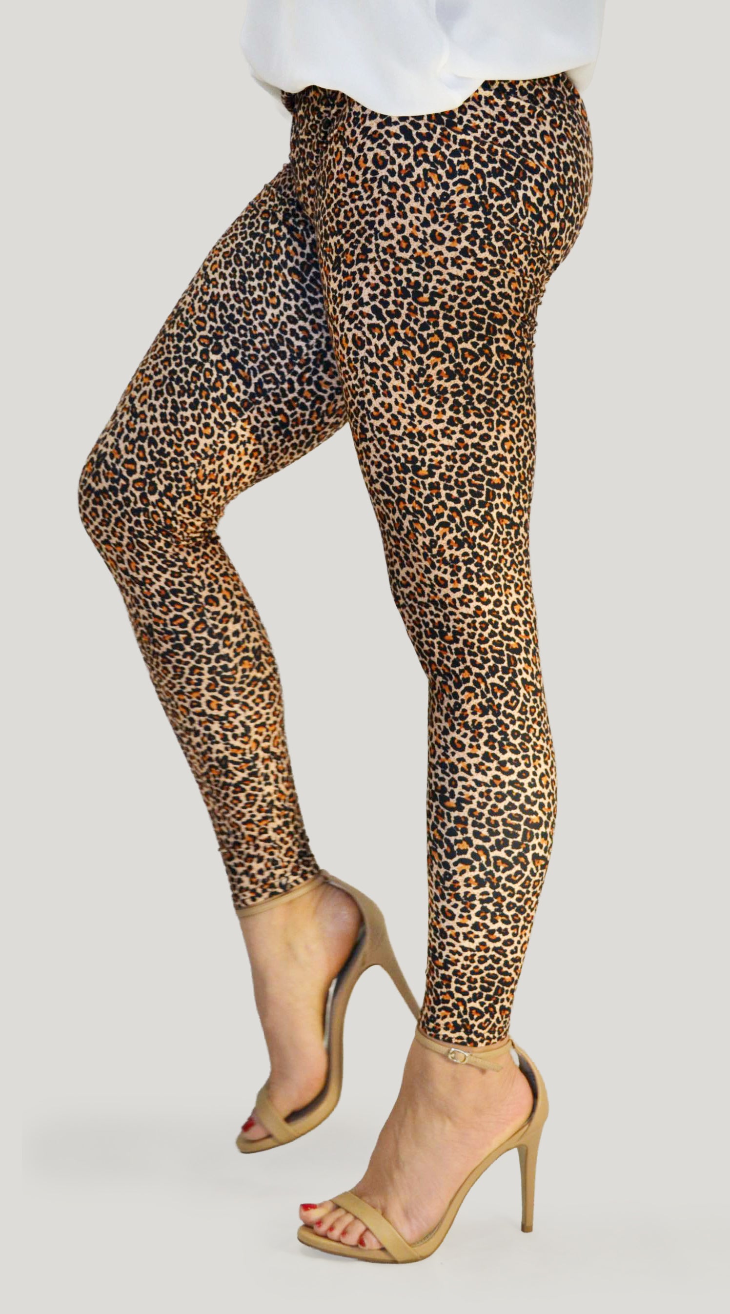 woman wearing high-waisted brown leopard print leggings paired with a black sports bra. Comfortable and stretchy animal print leggings perfect for workouts, yoga, or casual wear. Full-length design with a body-hugging fit, photographed barefoot in a studio with a neutral background.