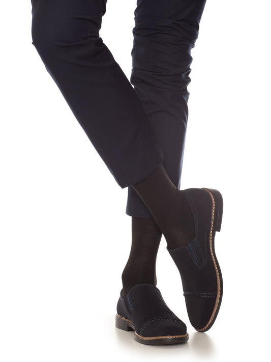 Man crossing legs while wearing black dress socks with navy dress pants and loafers, ideal for formal or business attire