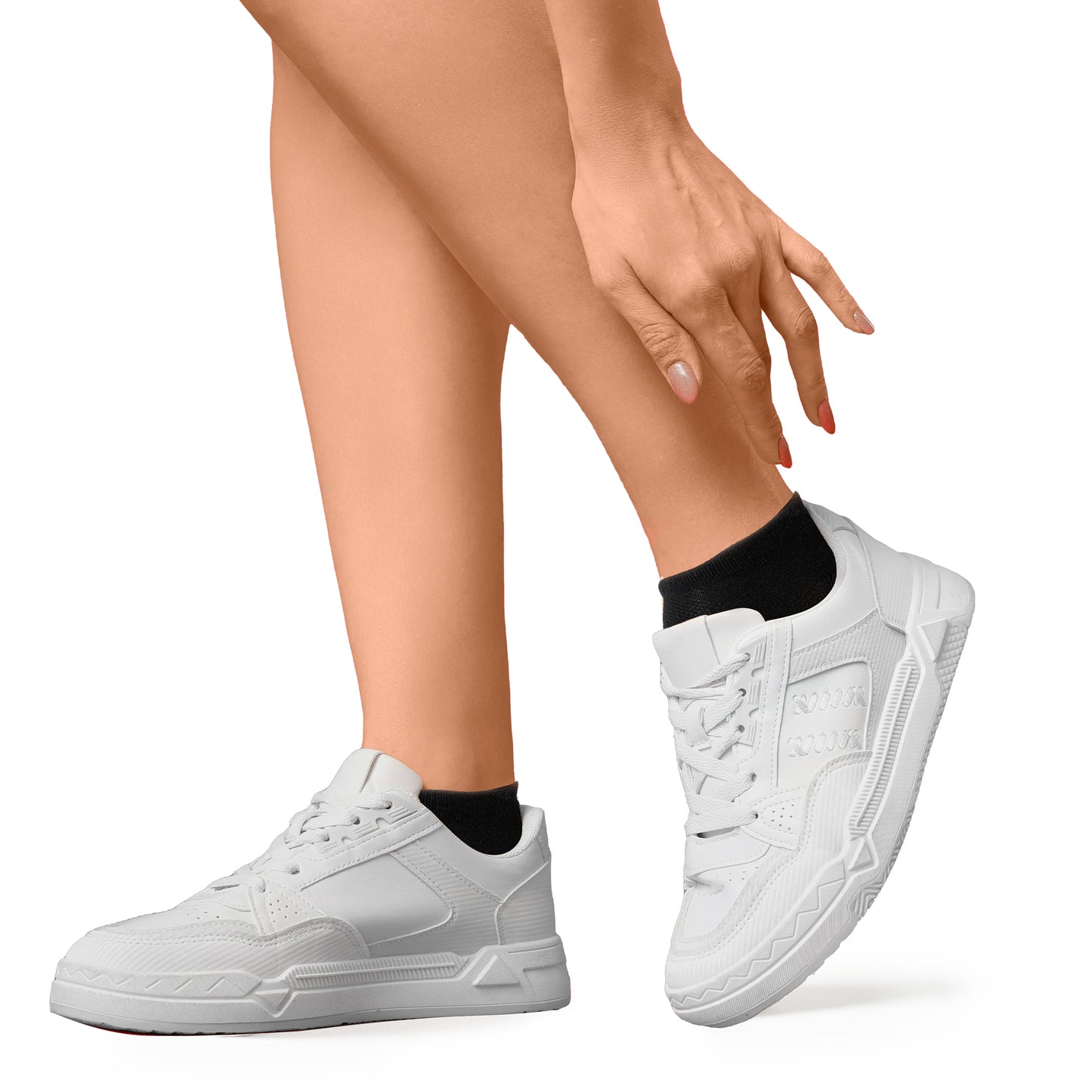 Woman posing in white sneakers and black low-cut athletic socks, reaching toward her ankle, showcasing casual sporty style ideal for walking, workouts, or everyday wear