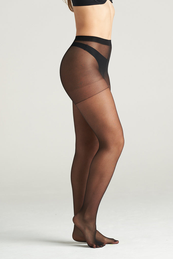 Woman modeling light support sheer hosiery in black tone, standing in a graceful side pose with one leg lifted, showcasing the smooth, semi-transparent finish and high-waisted support band