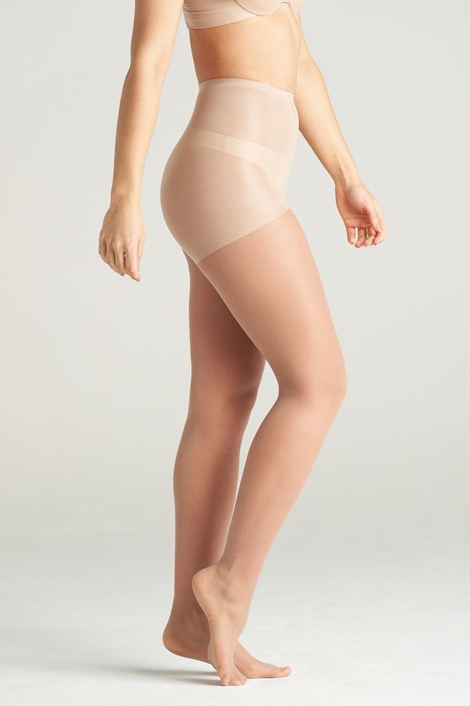 Woman modeling light support sheer hosiery in nude tone, standing in a graceful side pose with one leg lifted, showcasing the smooth, semi-transparent finish and high-waisted support band.