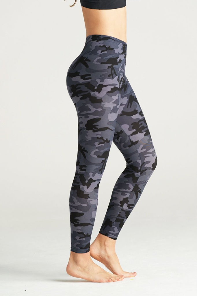 Woman wearing high-rise grey camouflage leggings with a sleek fit, paired with a black sports bra. She stands barefoot on a neutral studio backdrop, showcasing the leggings' bold grey, black, and charcoal camo pattern. Ideal for fitness, yoga, and everyday activewear.