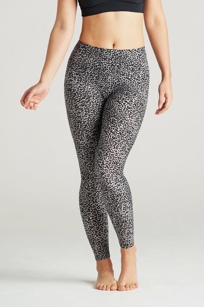 Plus-size woman wearing high-waisted brown cheetah print leggings paired with a black sports bra. Comfortable and stretchy animal print leggings perfect for workouts, yoga, or casual wear. Full-length design with a body-hugging fit, photographed barefoot in a studio with a neutral background.