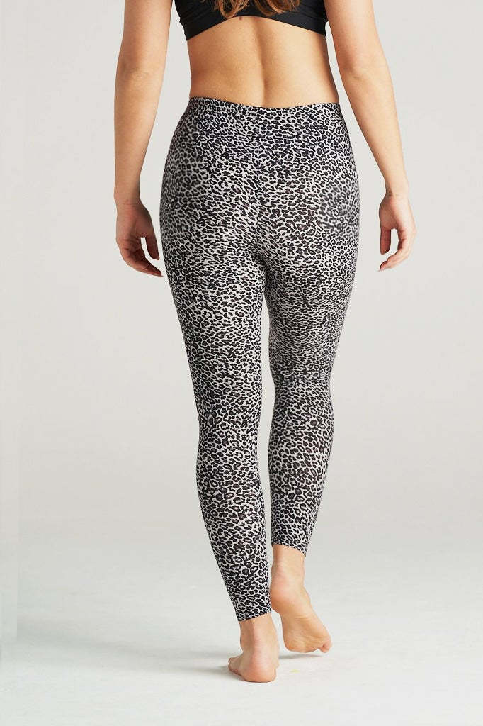 Plus-size woman wearing high-waisted brown cheetah print leggings paired with a black sports bra. Comfortable and stretchy animal print leggings perfect for workouts, yoga, or casual wear. Full-length design with a body-hugging fit, photographed barefoot in a studio with a neutral background.